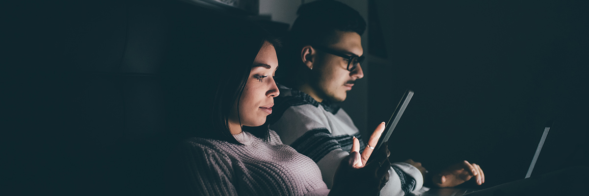 Couple looking at mobile devices in dark room
